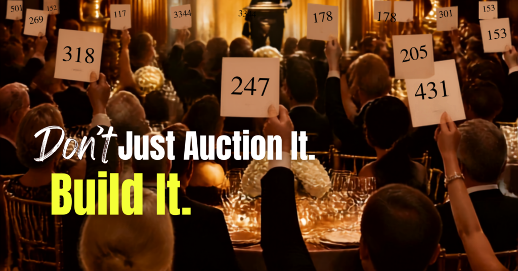 Guests raise bid paddles during a nonprofit live auction with the message “Don’t Just Auction It. Build It.”